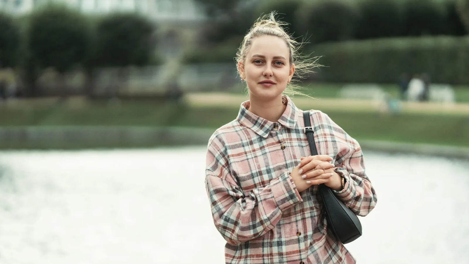 Jeune femme slave en extérieur au bord d'un lac, posture confiante — profil type des générations post-soviétiques, diplômées et autonomes.